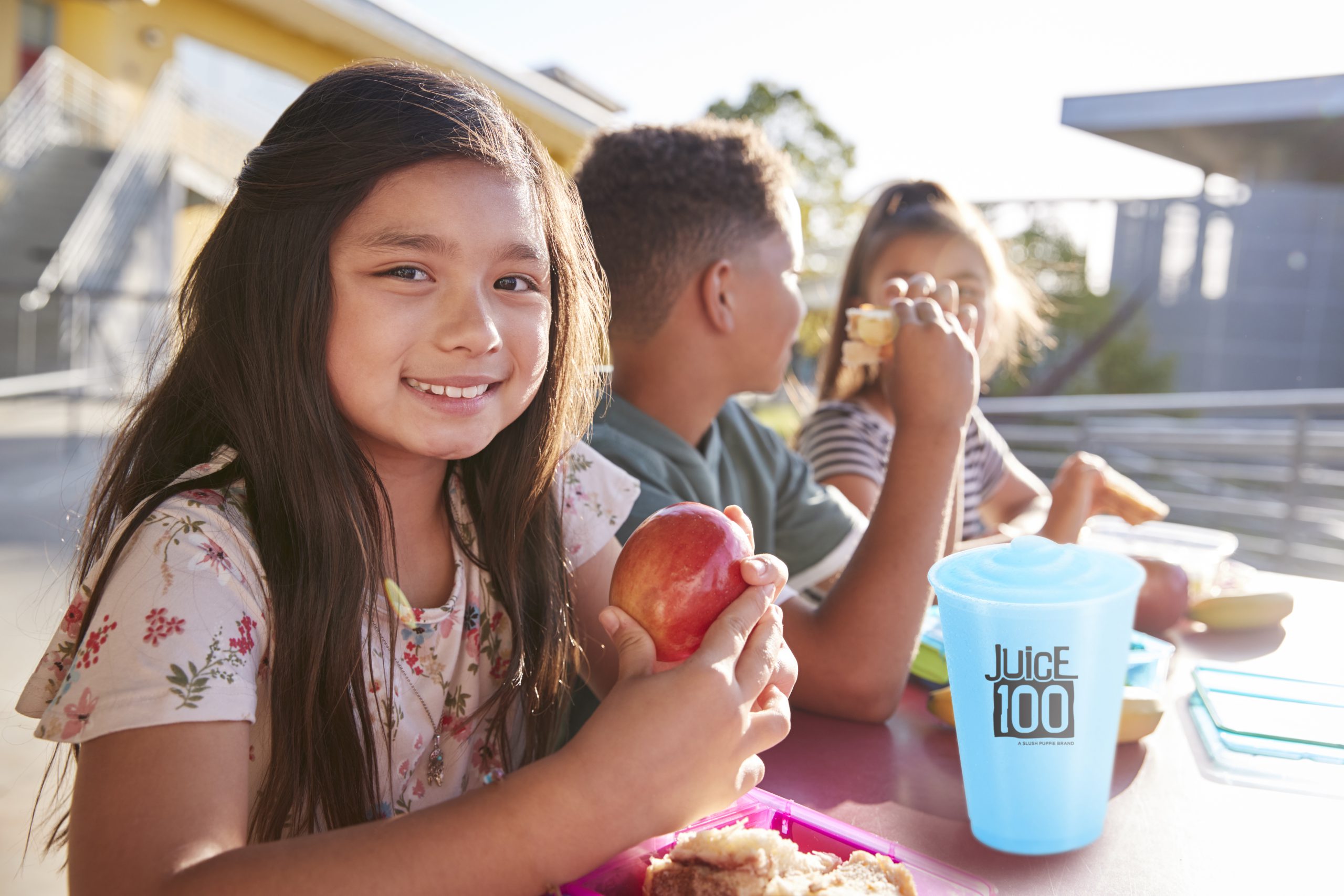 Girl at elementary school lunch table smiling to camera