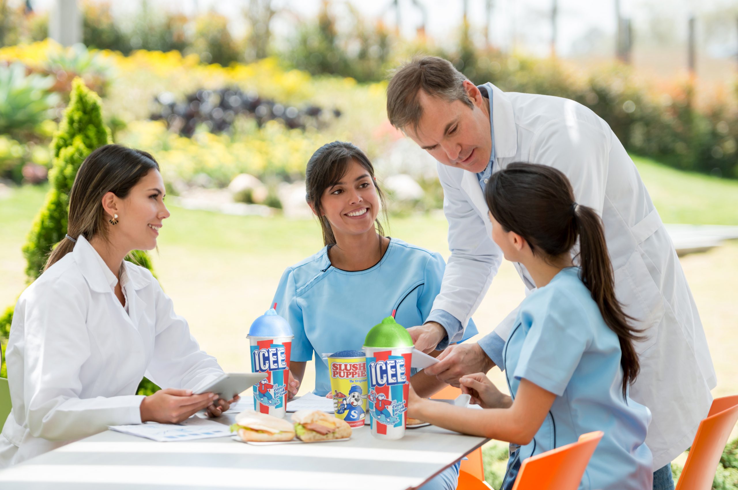 Group of doctors gathered and nurses at the cafeteria talking about patients and having a bite